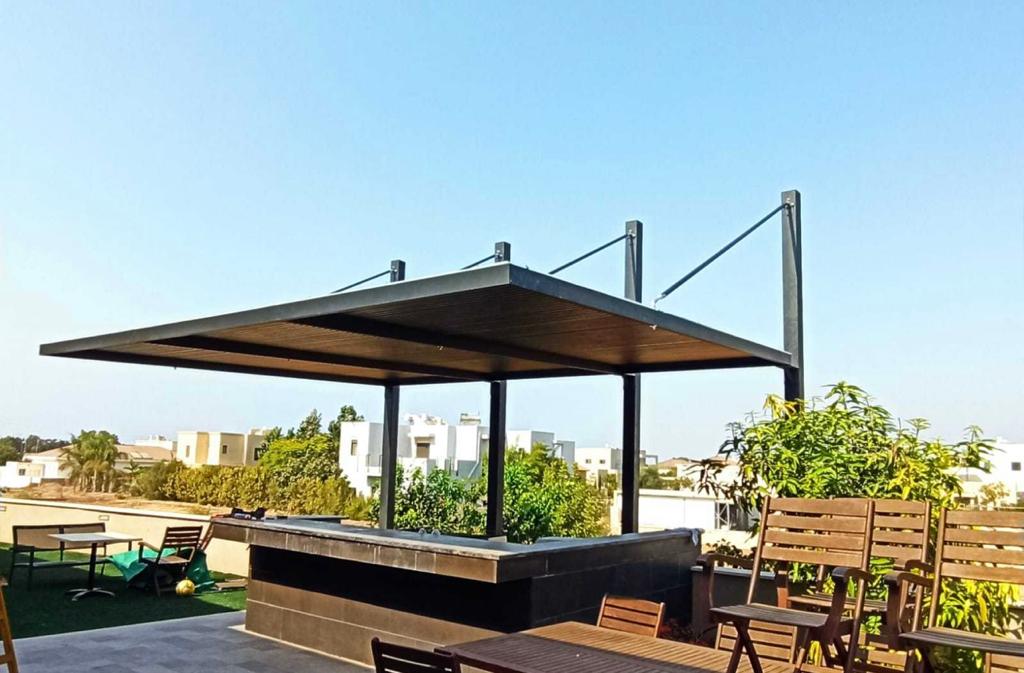 פרגולה עומדת על עמודים עם רפפות כהות על מרפסת גג
