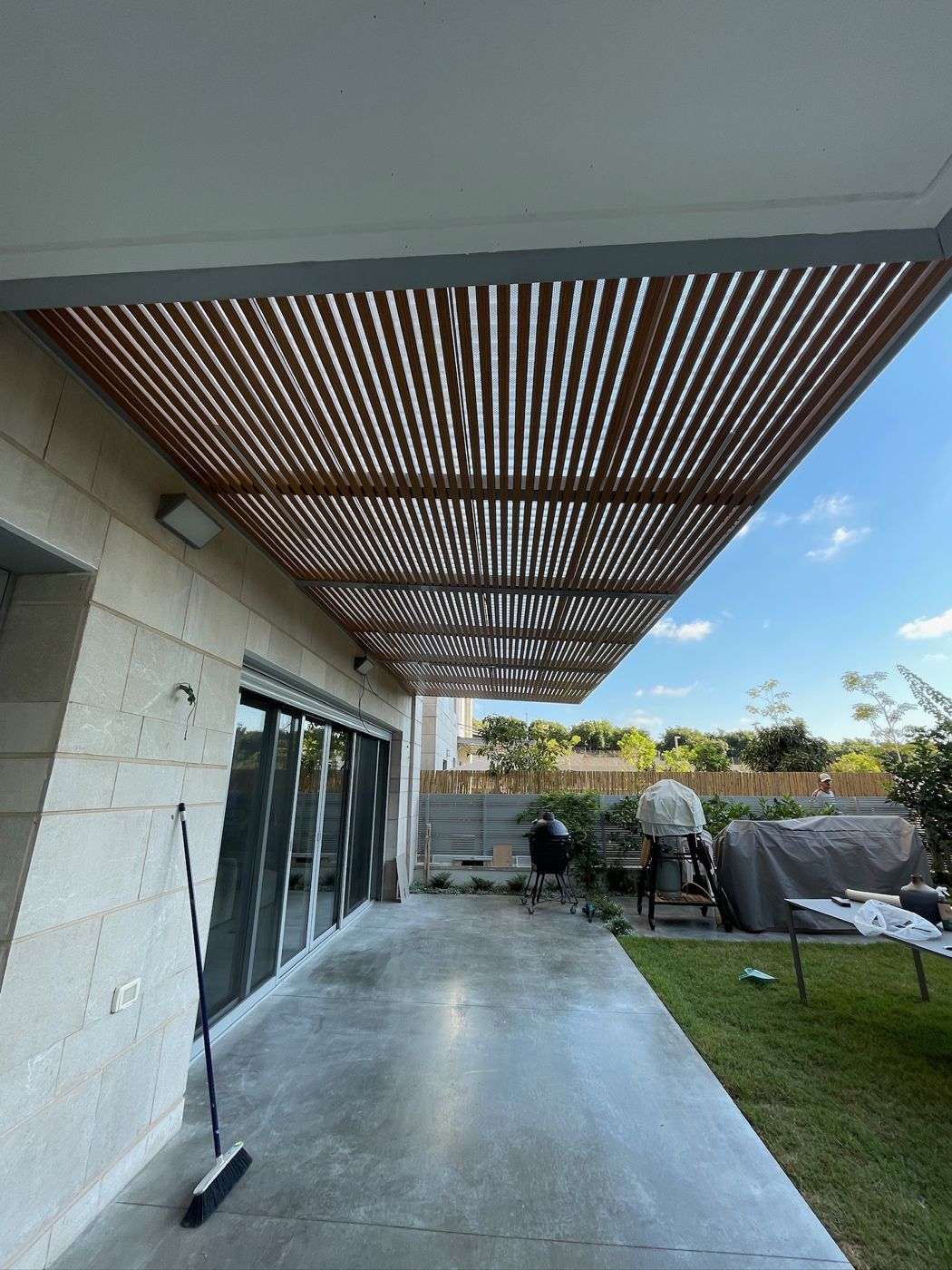 פרגולת אלומיניום בגוון עץ מעל פטיו וגינה בהרצליה