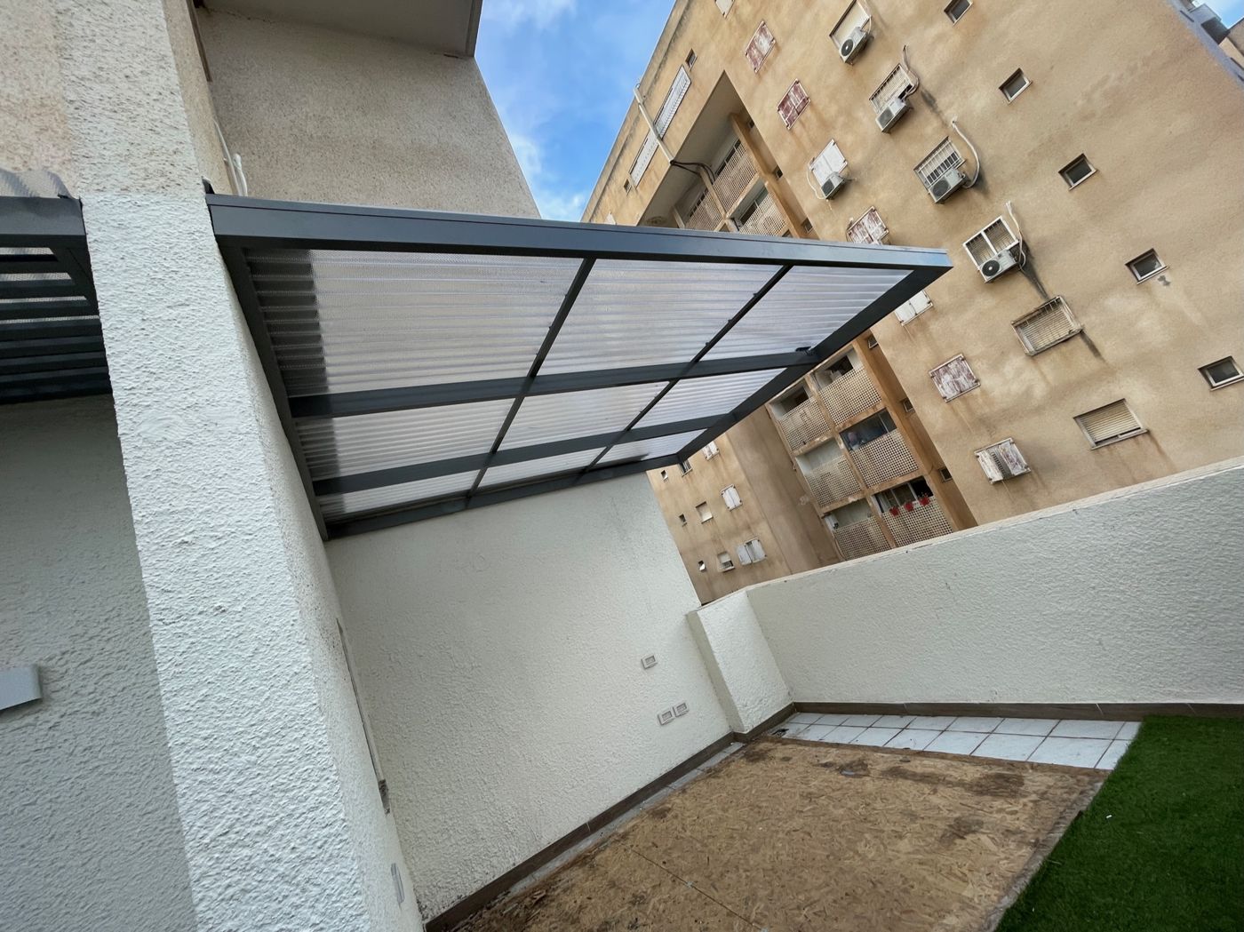 פרגולת אלומיניום כהה עם נוף בנייני מגורים בכפר סבא