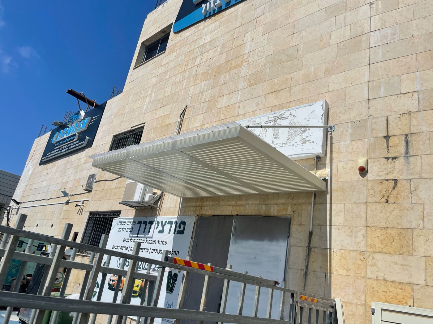 רפפות אלומיניום כהות של פרגולה על רקע שמיים כחולים באור עקיבא