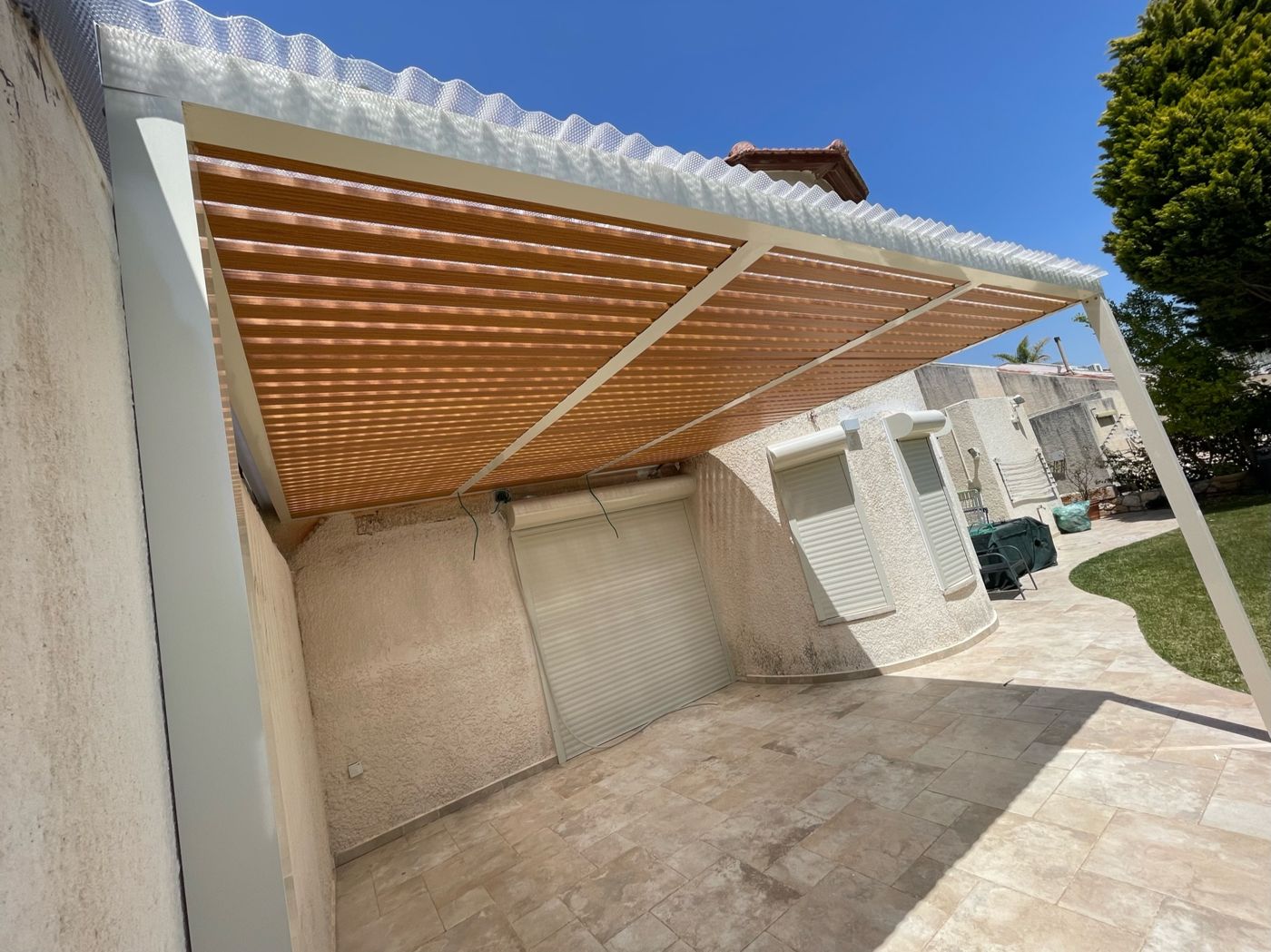 פרגולת אלומיניום עם רפפות בגוון עץ ליד עץ בראש העין