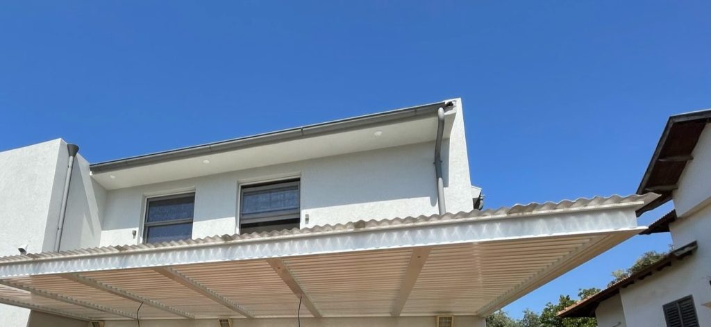 מבט מלמטה על רפפות אלומיניום קבועות וסינר קדמי מעוצב של פרגולה בעין שריד
