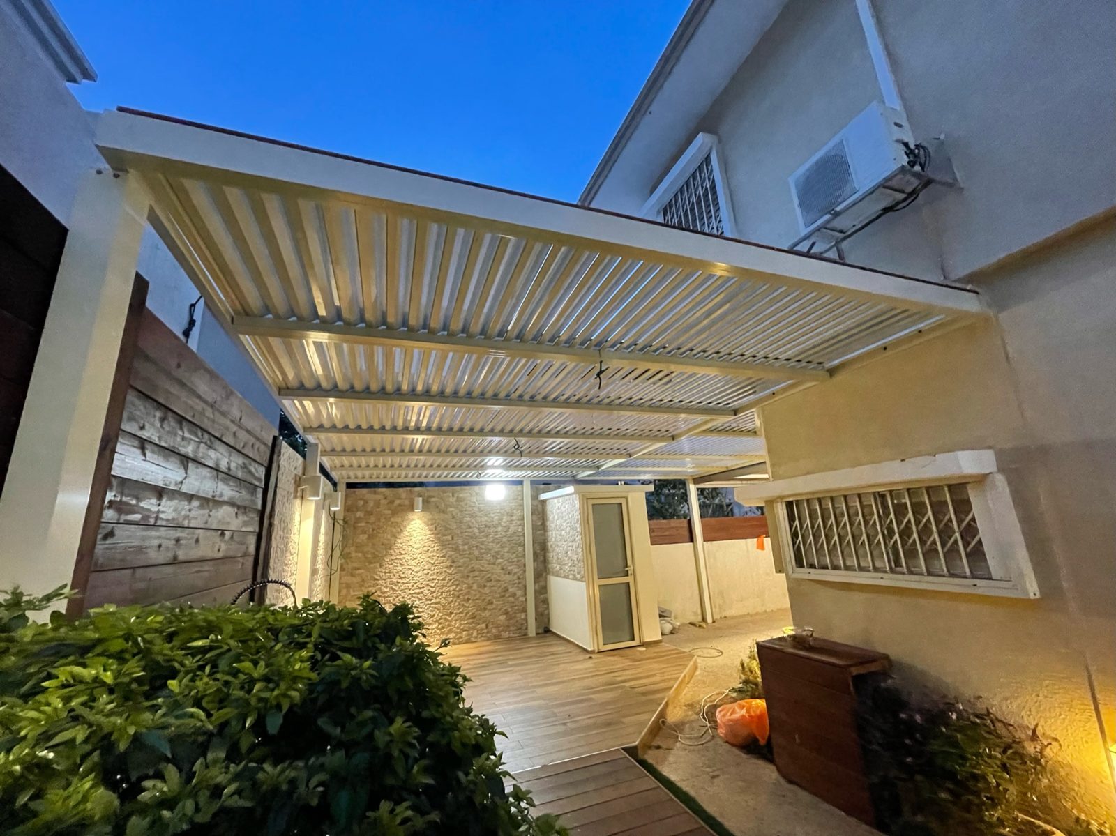 פטיו מקורה בפרגולת אלומיניום עם תאורה בשעת בין ערביים בחדרה