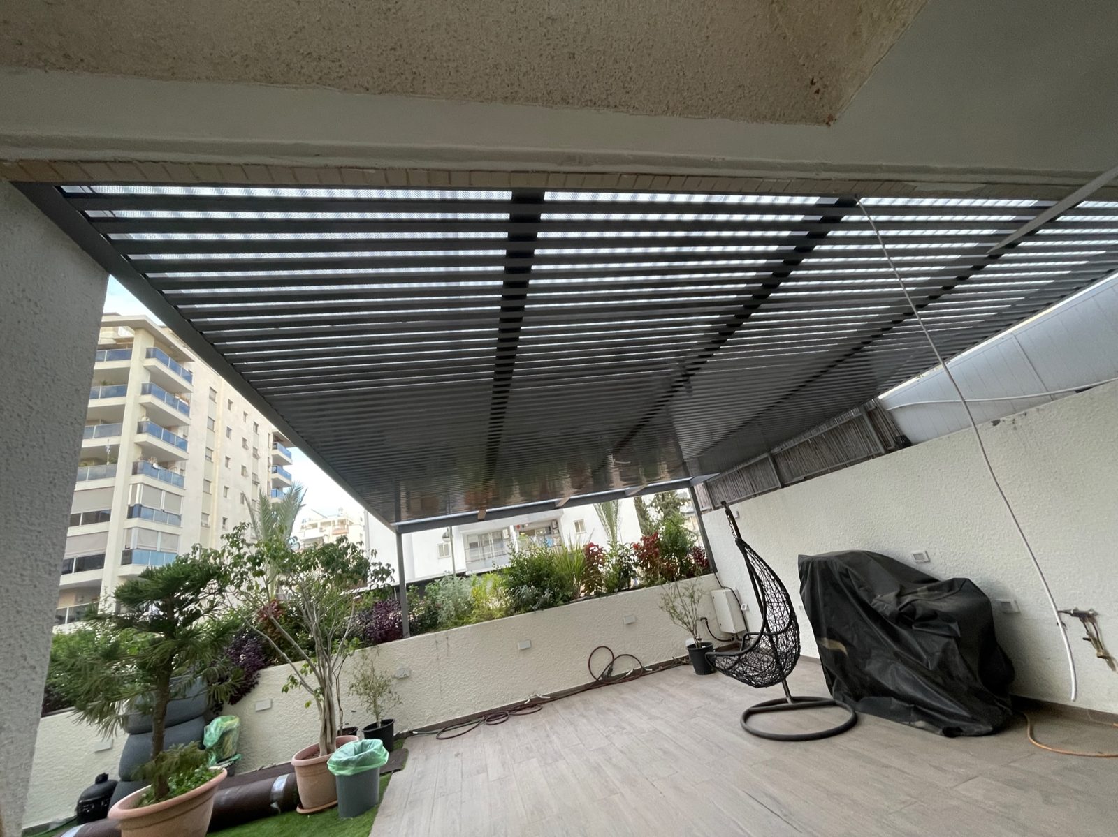 מרפסת ארוכה מקורה בפרגולת אלומיניום עם נוף העיר בכפר סבא