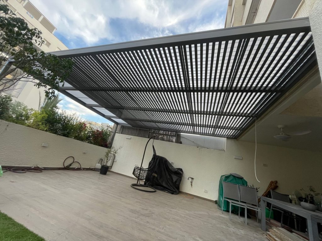 פרגולת אלומיניום כהה מעל מרפסת עם גינה בכפר סבא